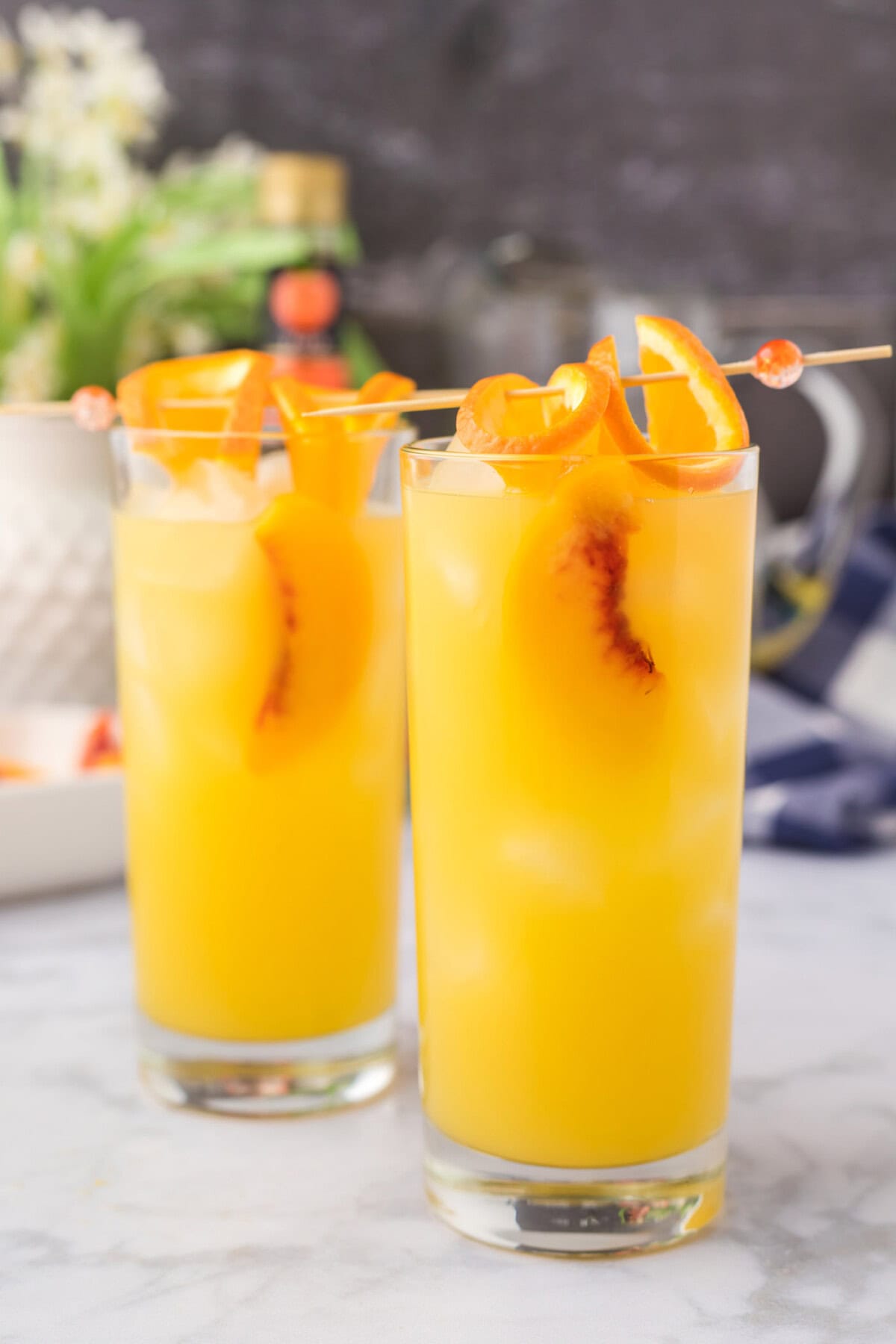 fuzzy navel cocktail with skewered orange slices and peach slices