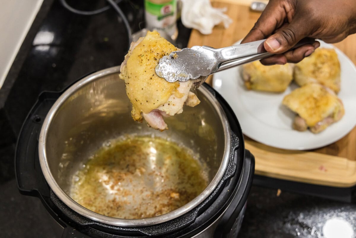 seared chicken on tongs over instant pot