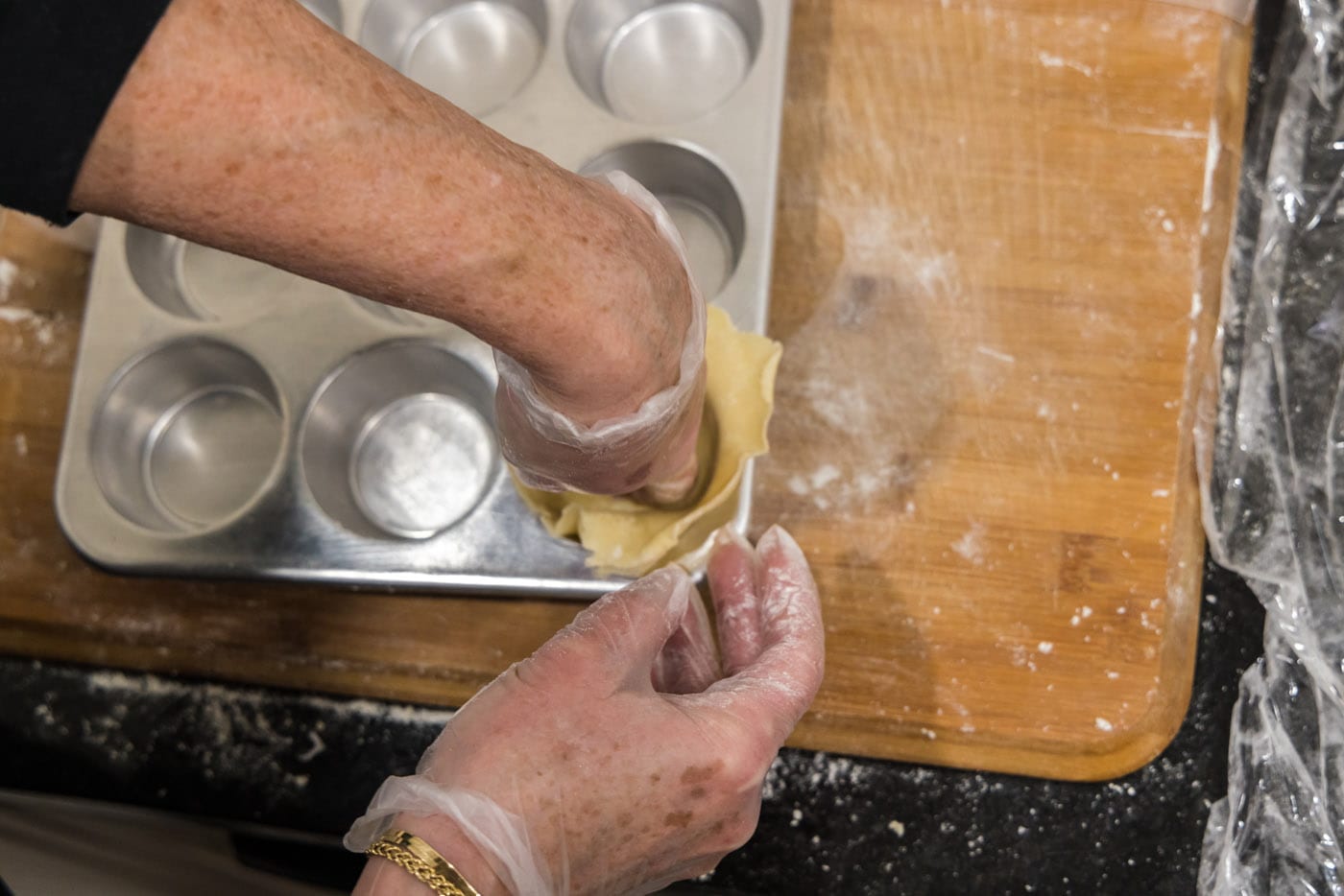 hand pressing dough ball into muffin cavity