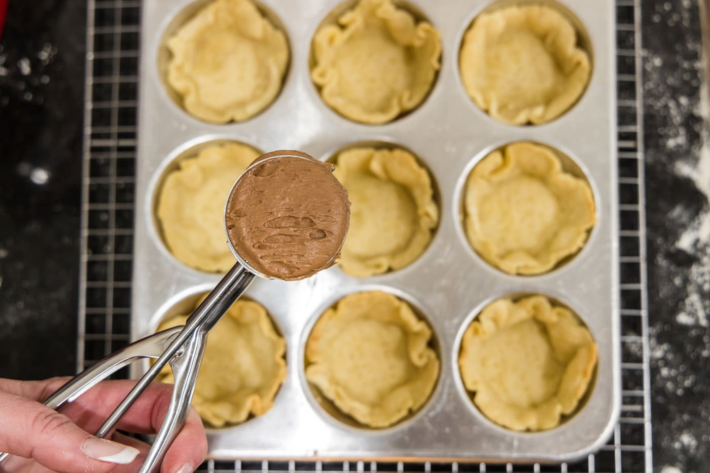 scooping french silk filling into mini pie crusts