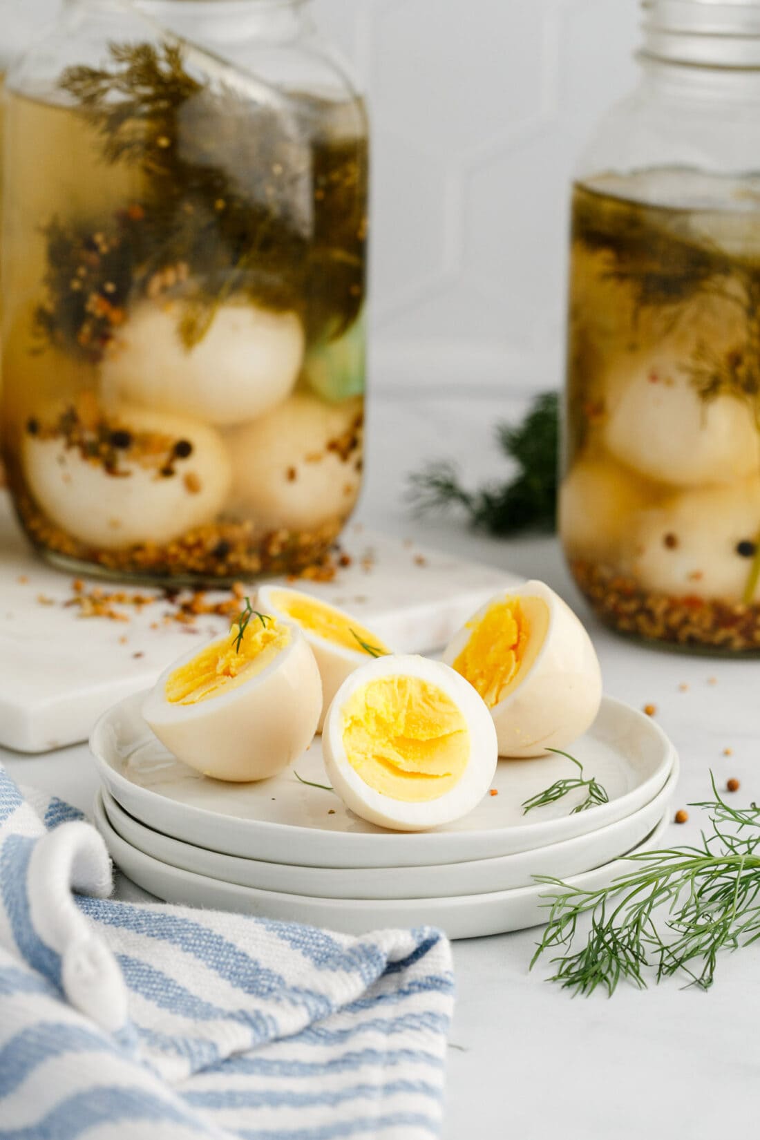 Two Pickled Eggs cut in half on a plate with jars of Pickled Eggs in the background