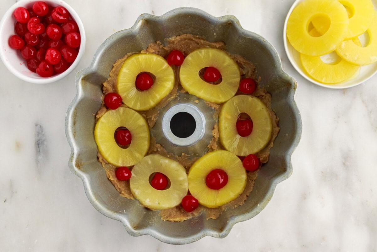 maraschino cherries added on top of pineapple rings in a bundt pan