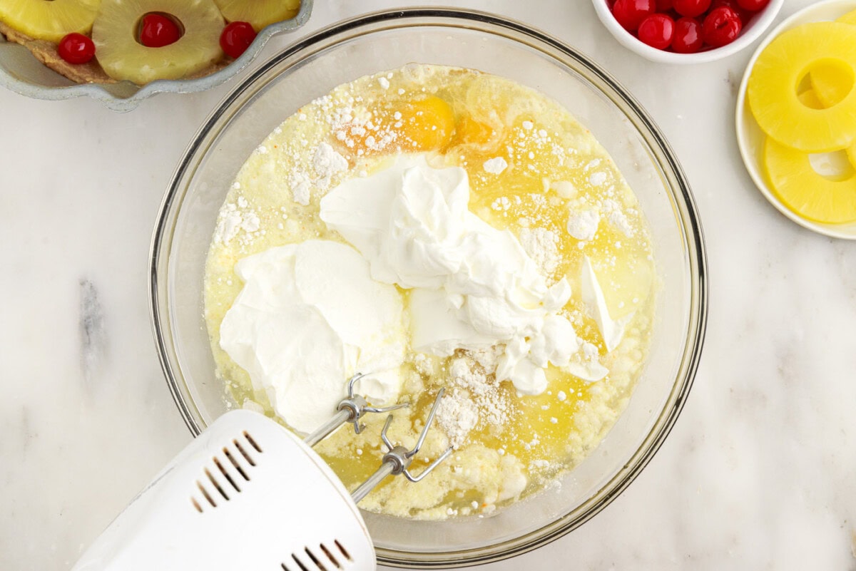 mixing bundt cake ingredients with a handheld mixer