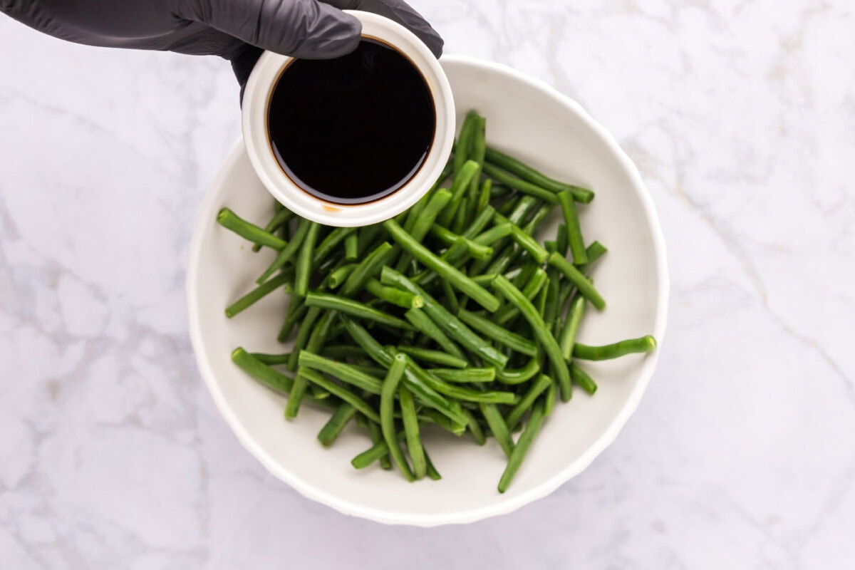 soy sauce over green beans in a bowl