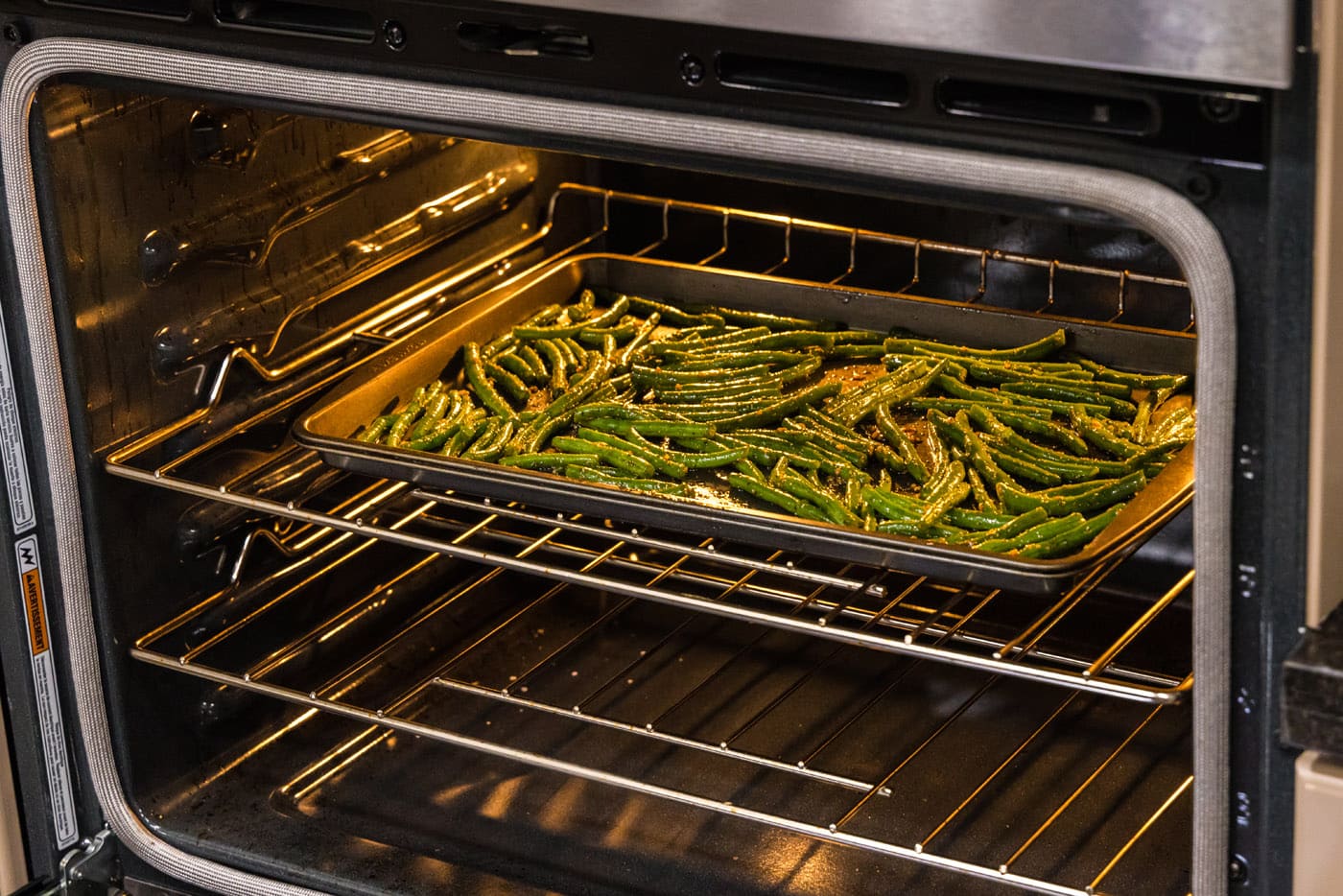 roasted green beans on a baking sheet in the oven