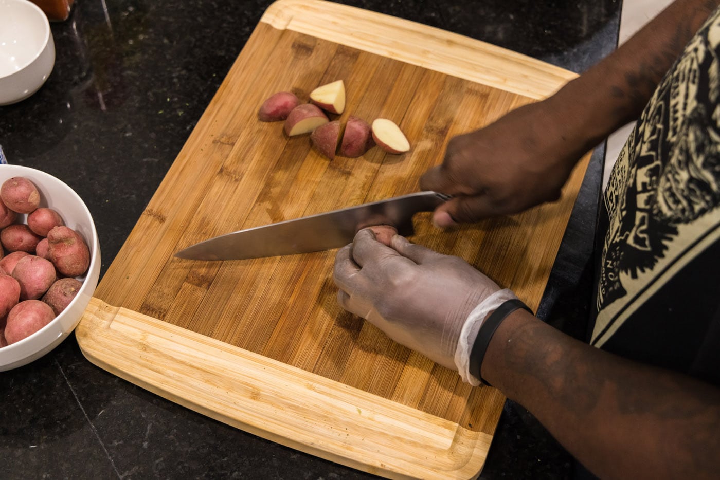 hands slicing baby red potatoes on a cutting board