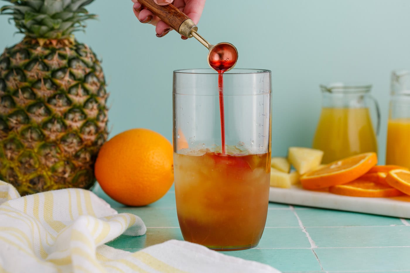 adding grenadine to cocktail glass with rum and liqueur