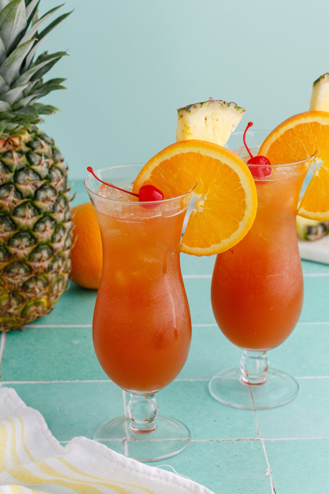 Two Rum Runners garnished with an orange wheel, pineapple wedge and cherry