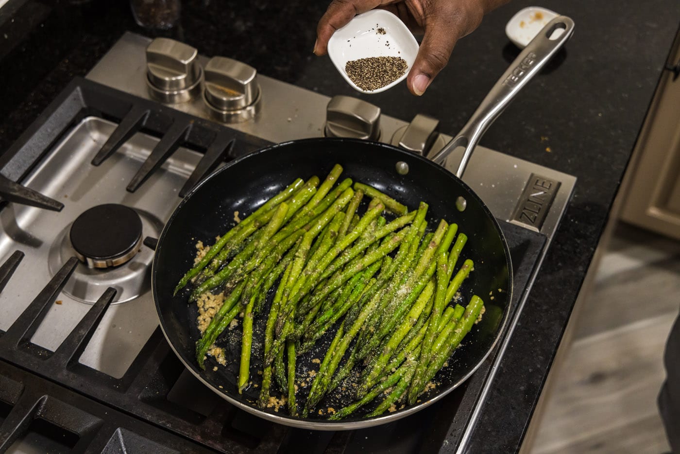 adding pepper to sauteed asparagus