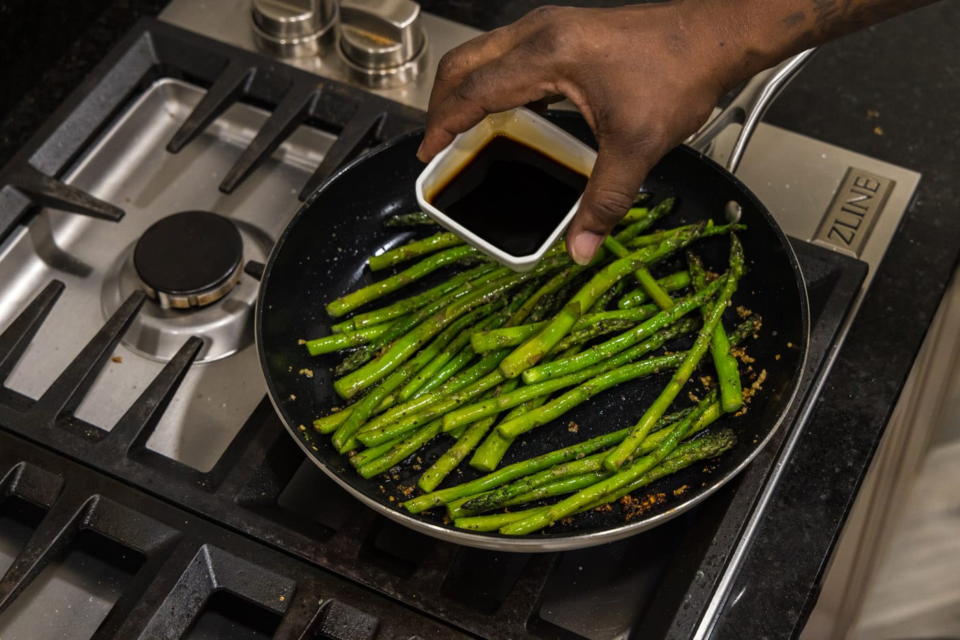 adding soy sauce to sauteed asparagus