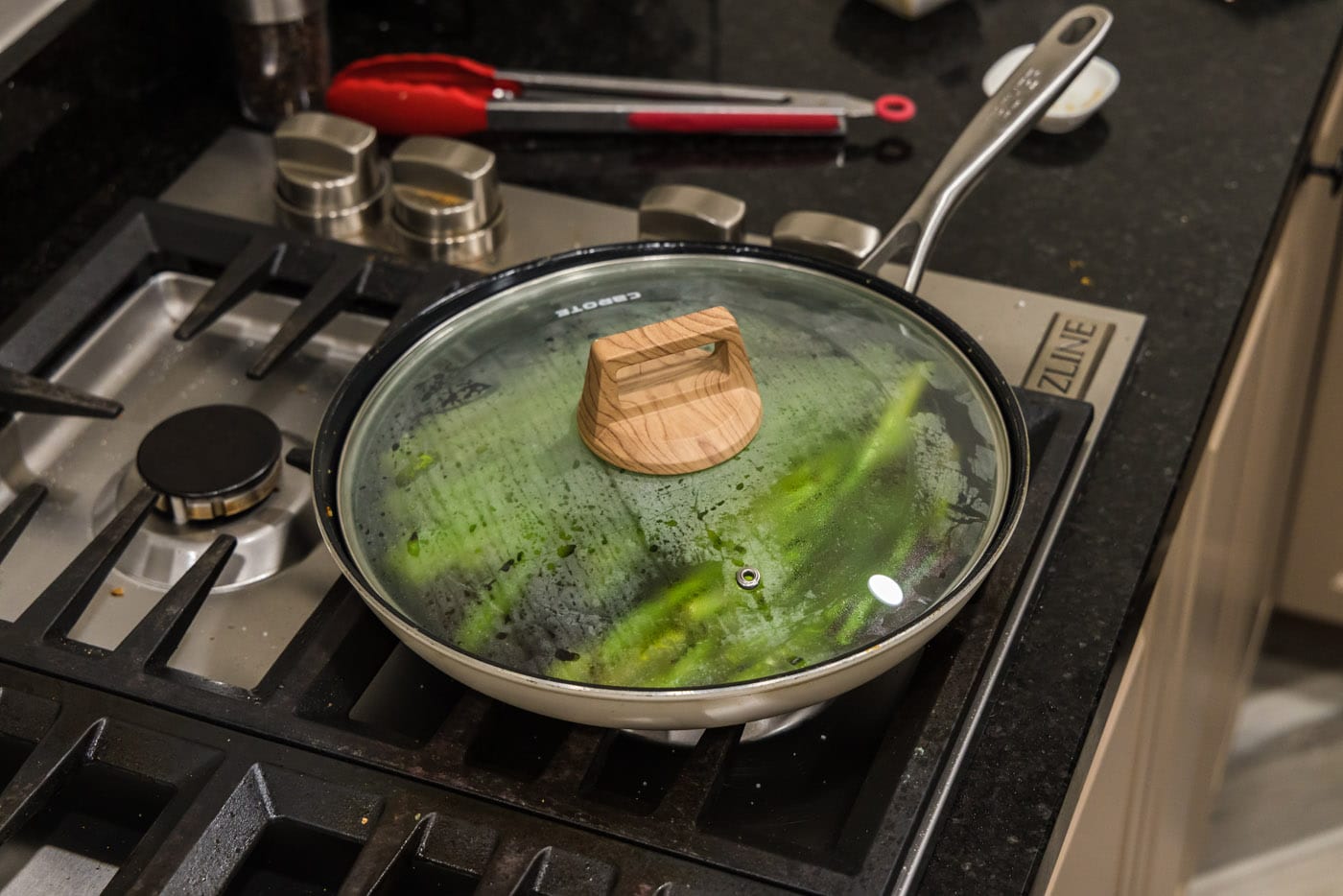 lid covering asparagus in a skillet