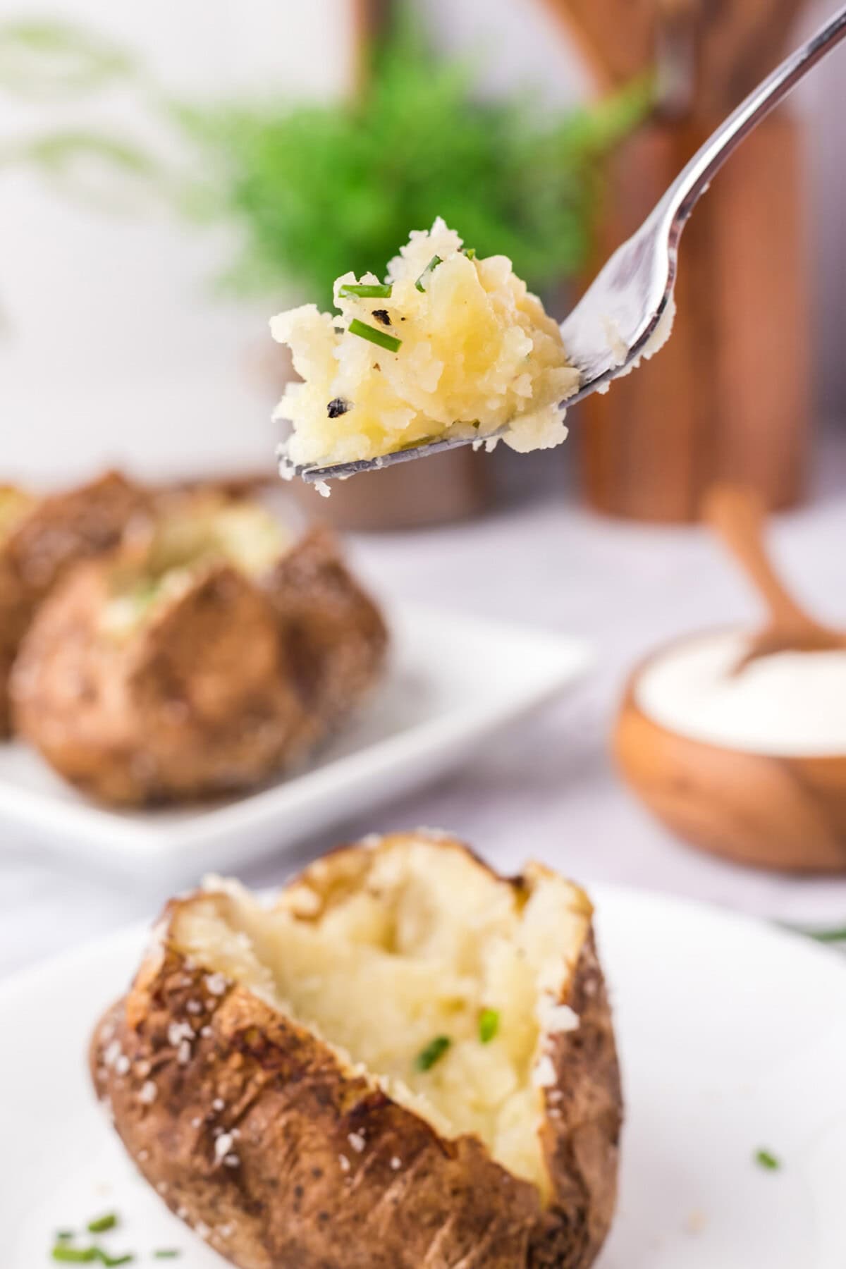 Piece of Baked Potato on a fork held above a spilt open Baked Potato