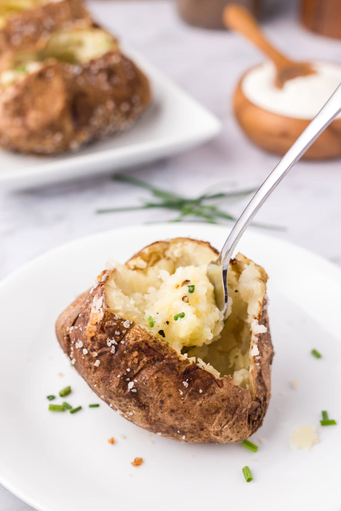 Baked Potato split open on a plate with a fork in it