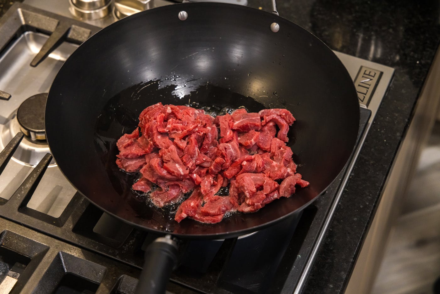 flank steak strips in a wok with oil