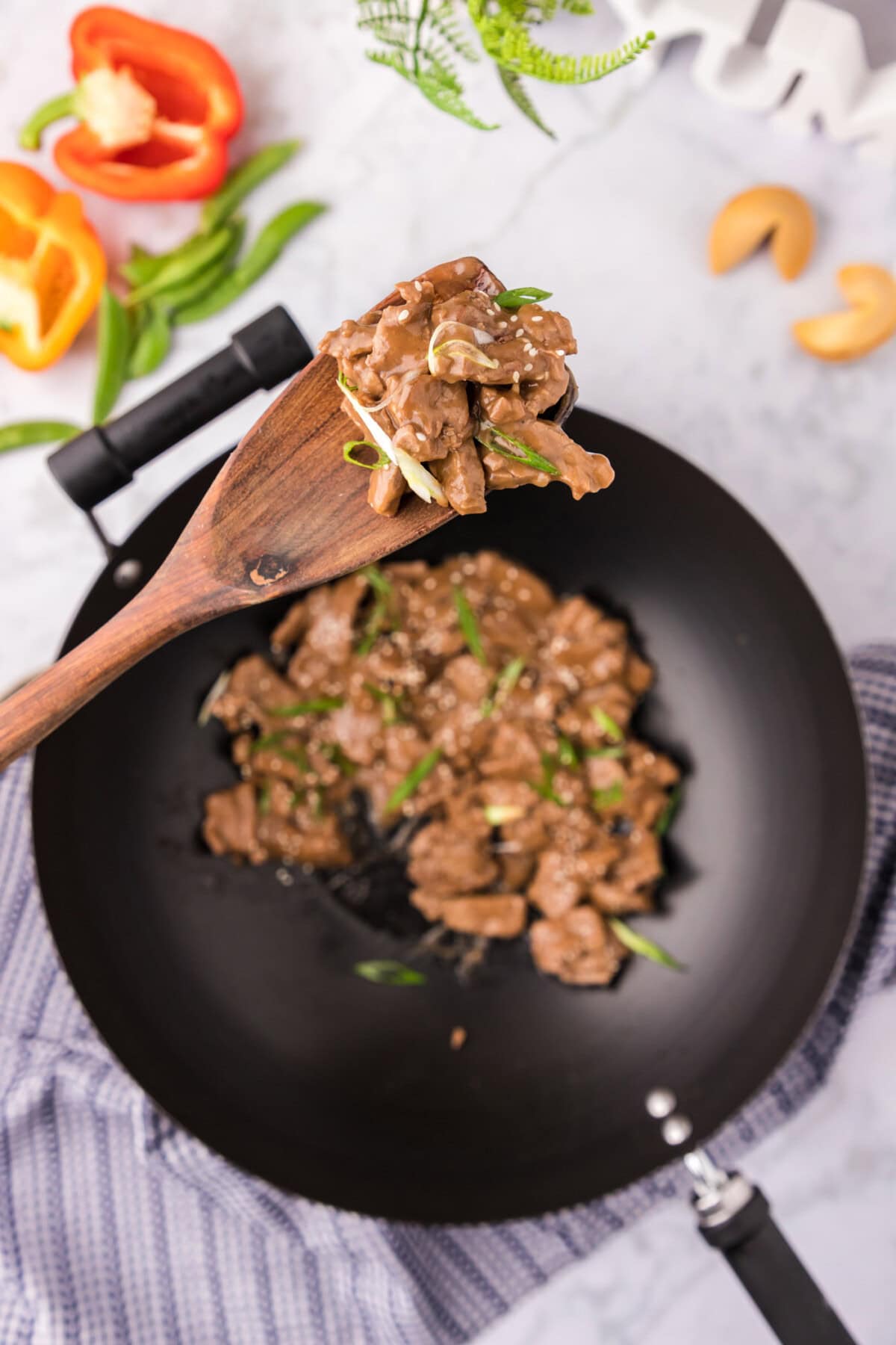 Spoonful of Beef Teriyaki held above a skillet of Beef Teriyaki
