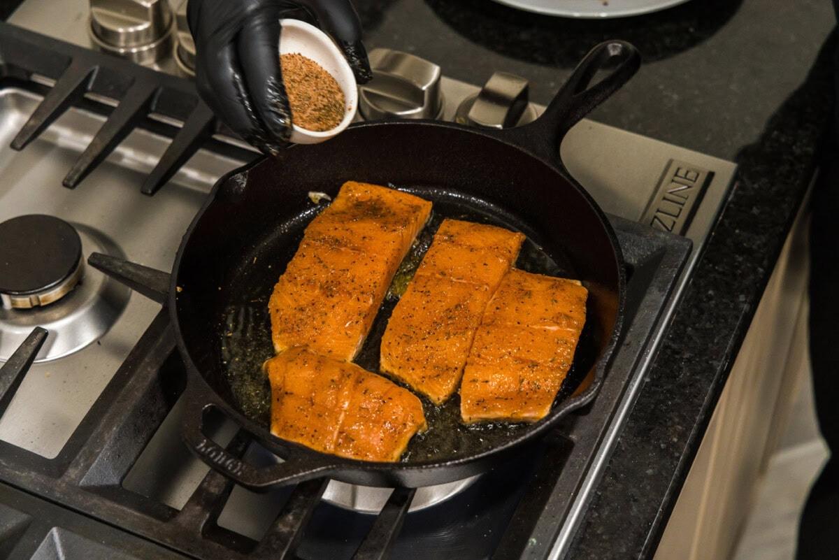 hand sprinkling cajun seasoning onto salmon filets