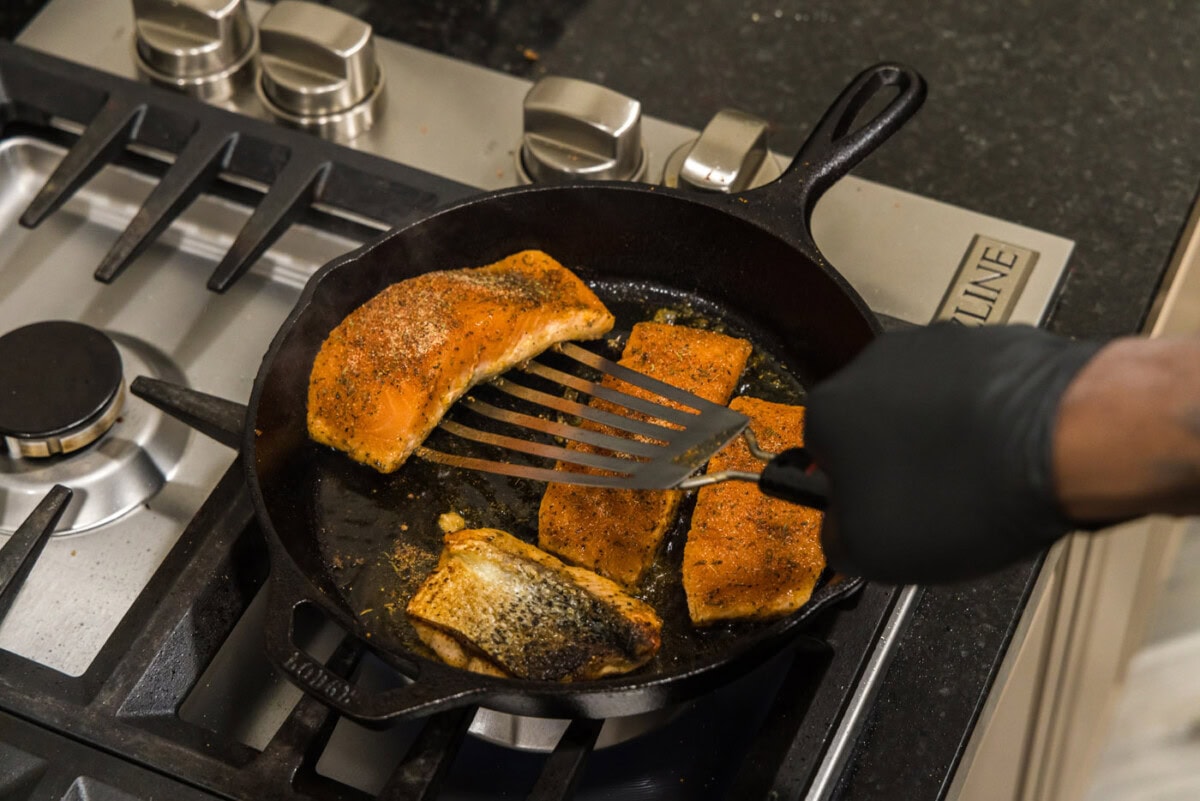 fish turner flipping salmon filets in a skillet