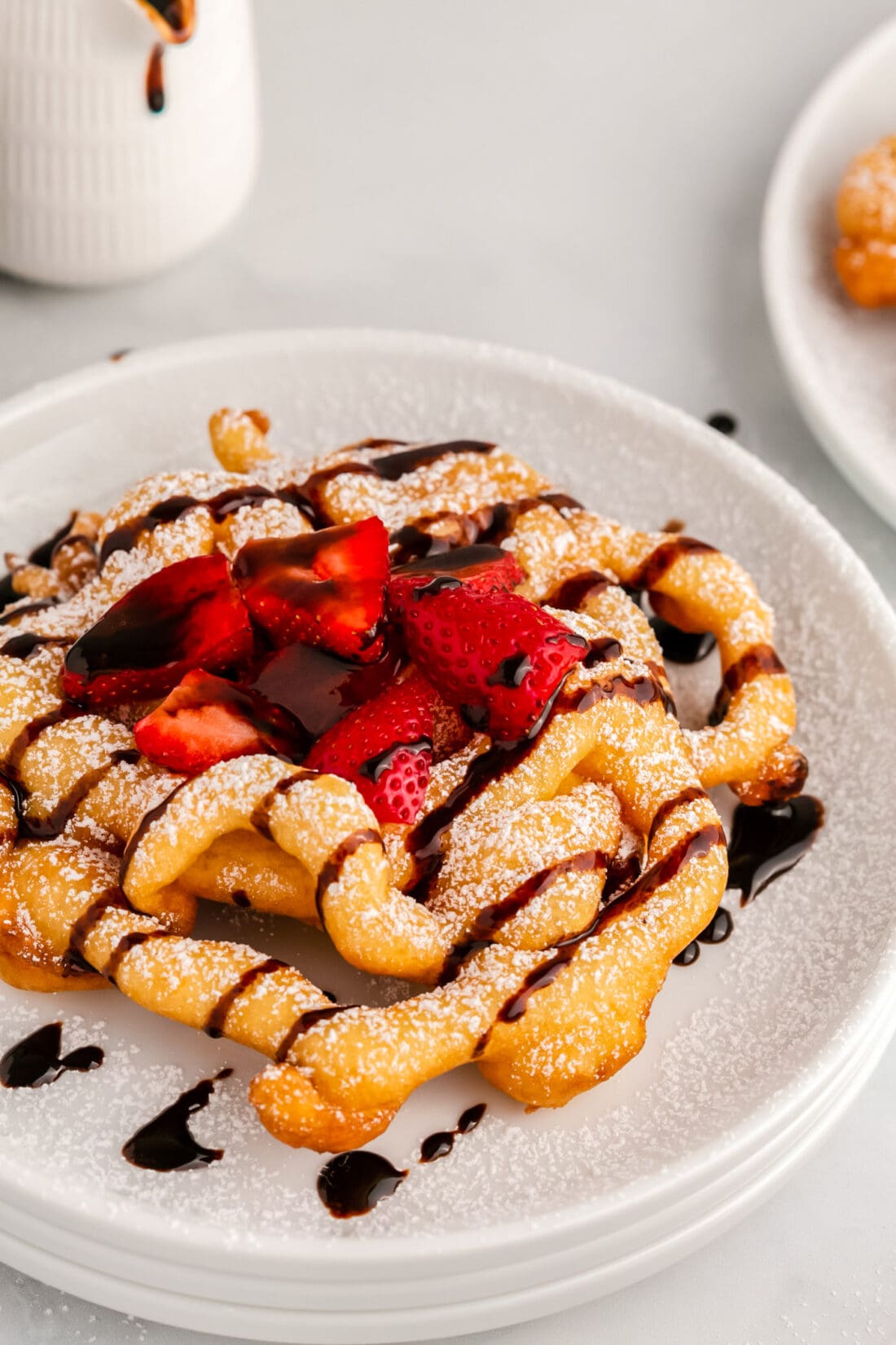 Close up photo of a Funnel Cake topped with chocolate sauce and strawberries