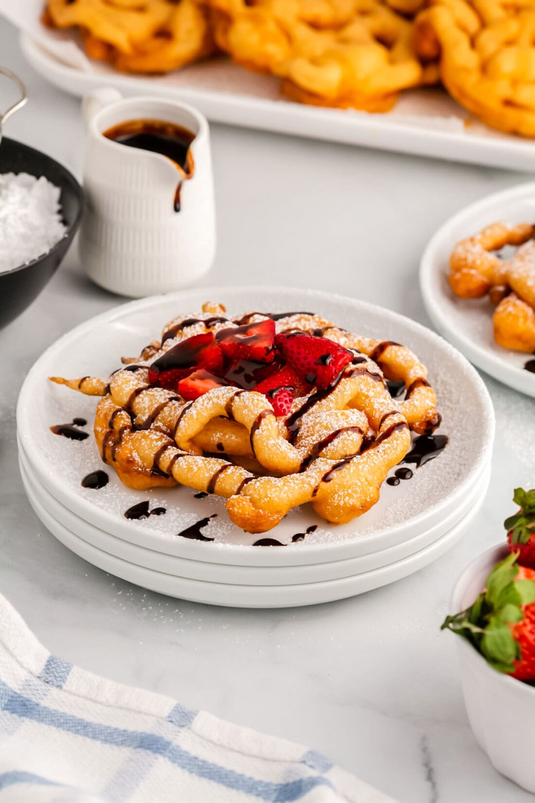 Funnel Cake topped with powdered sugar, chocolate sauce and strawberries