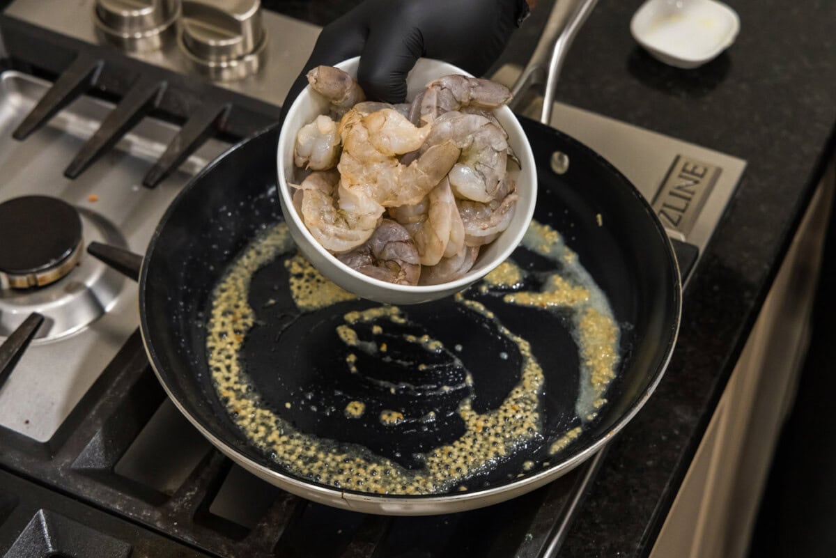 adding raw shrimp to skillet with garlic butter