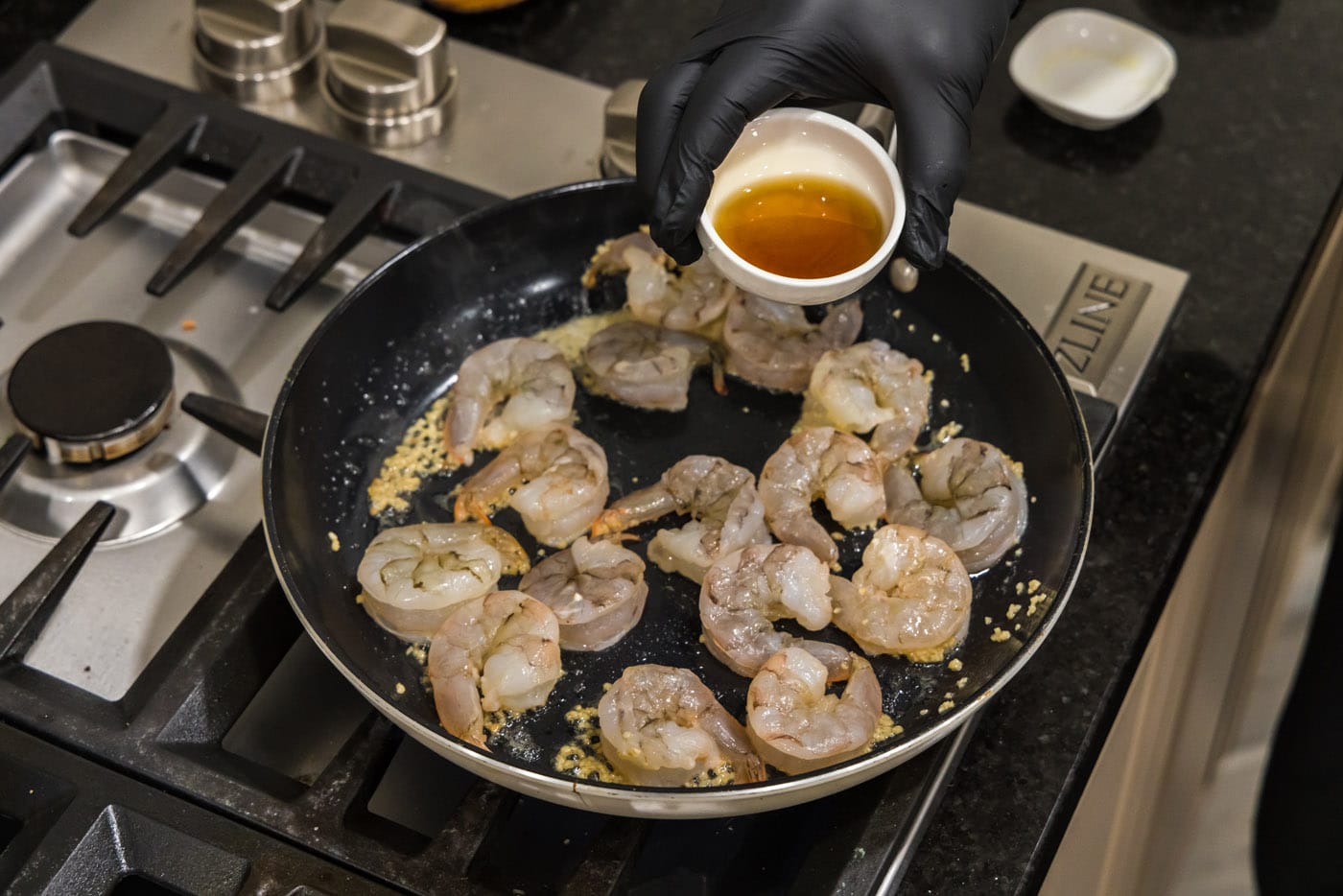 adding sauce to skillet with shrimp