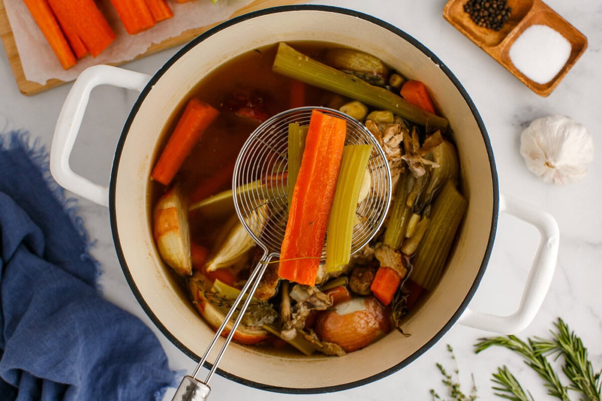 using a strainer to remove vegetables from stock