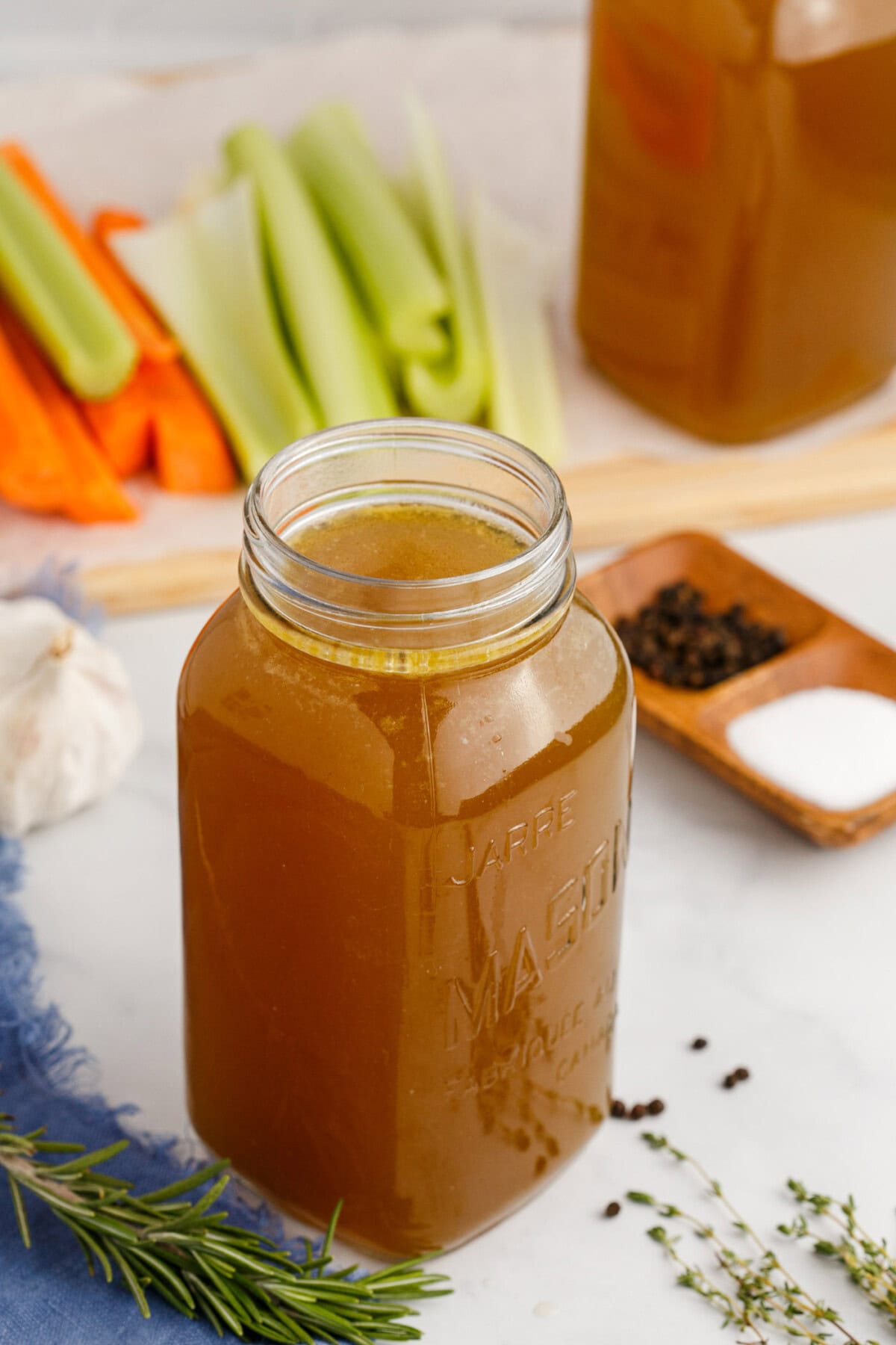 Jar of Homemade Chicken Stock with carrots and celery in the background