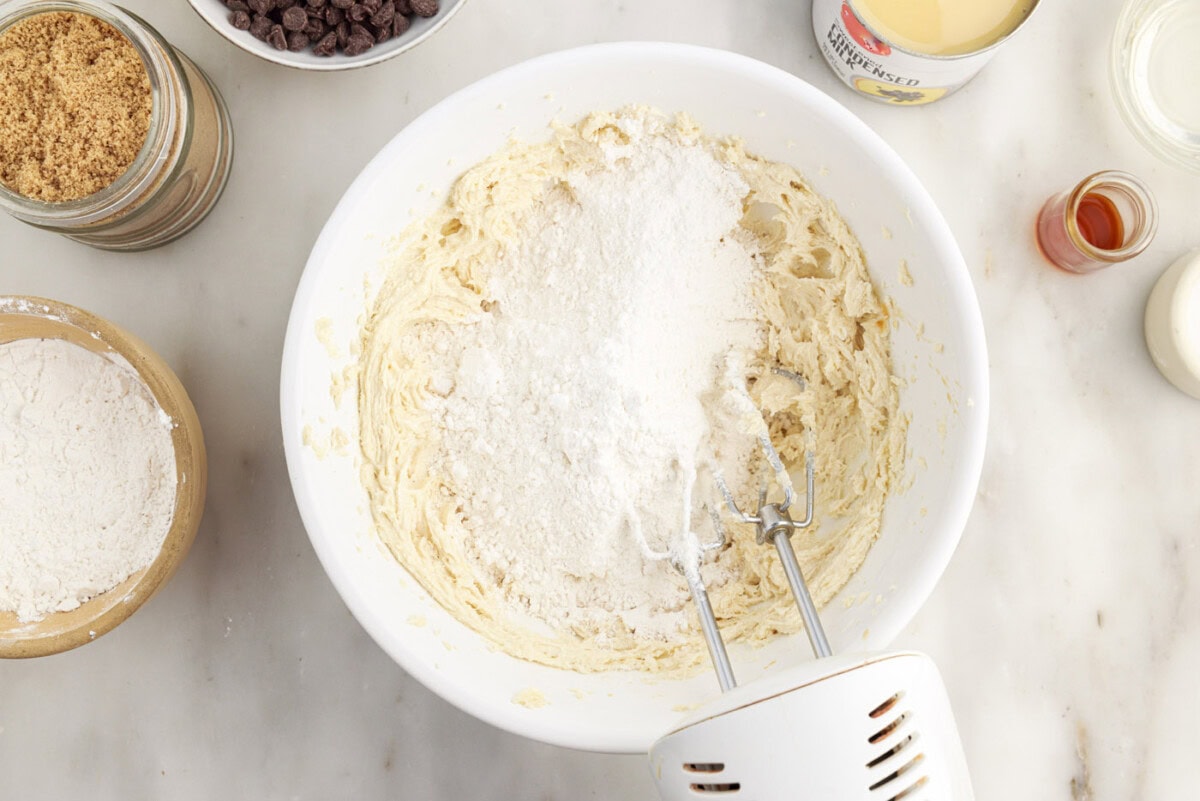 adding flour to shortbread dough in a bowl
