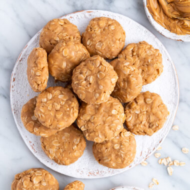 No Bake Peanut Butter Cookies on a plate with a bowl of peanut butter on the side