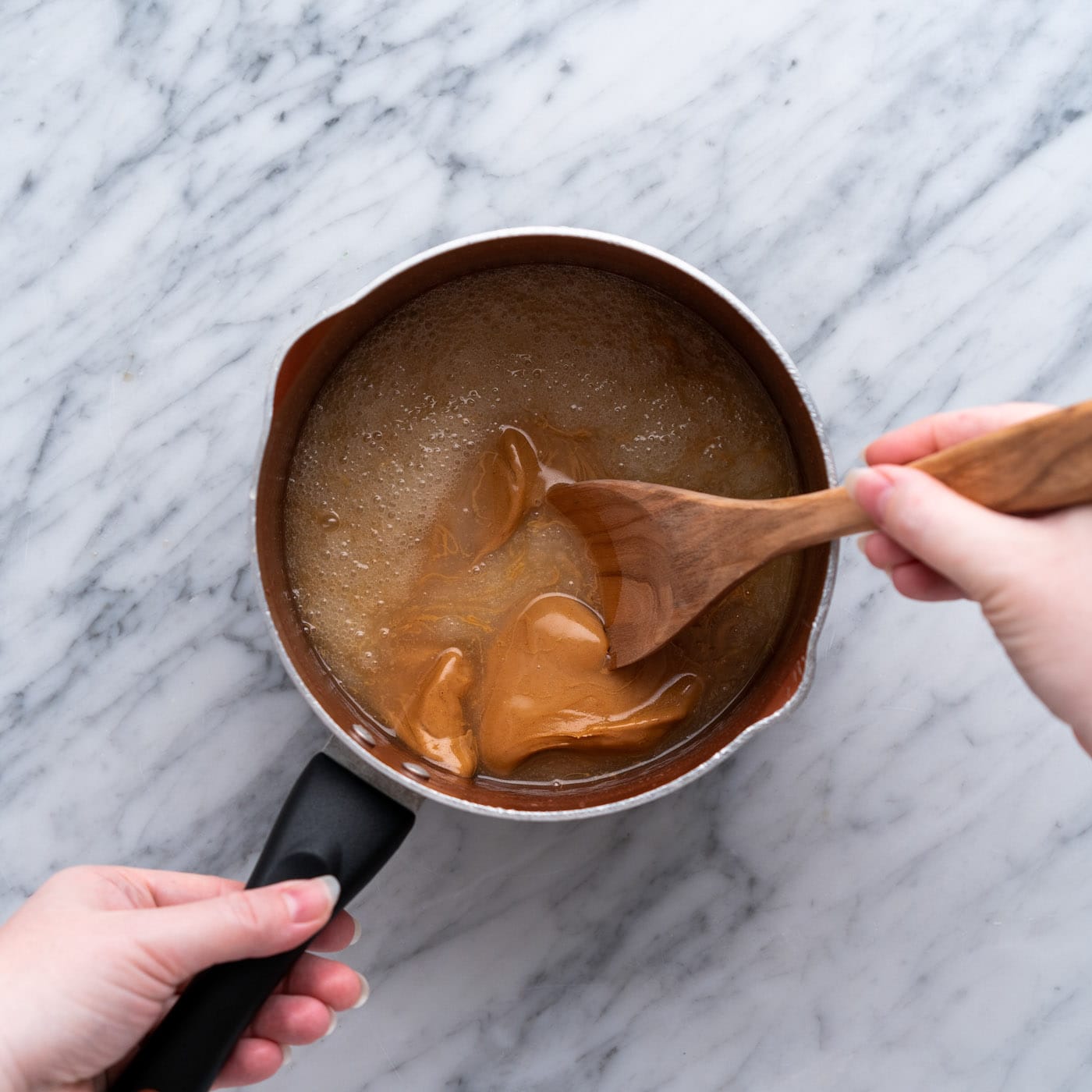 wooden spoon stirring peanut butter cookie mixture in a pan