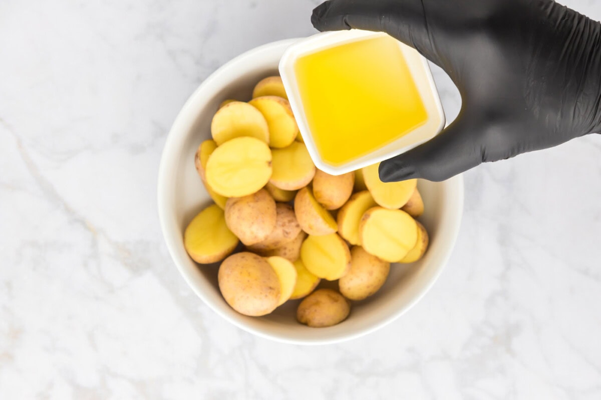 olive oil over sliced potatoes in a bowl