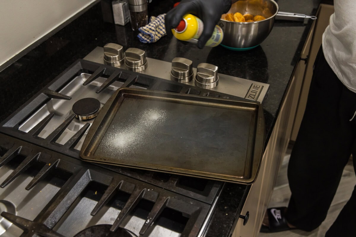 spraying a baking sheet with cooking spray