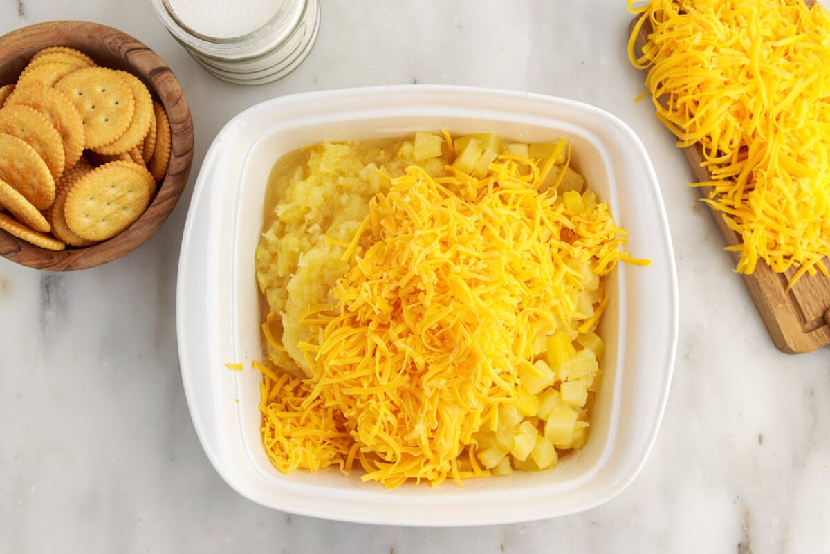 grated cheddar cheese and pineapple added to baking dish