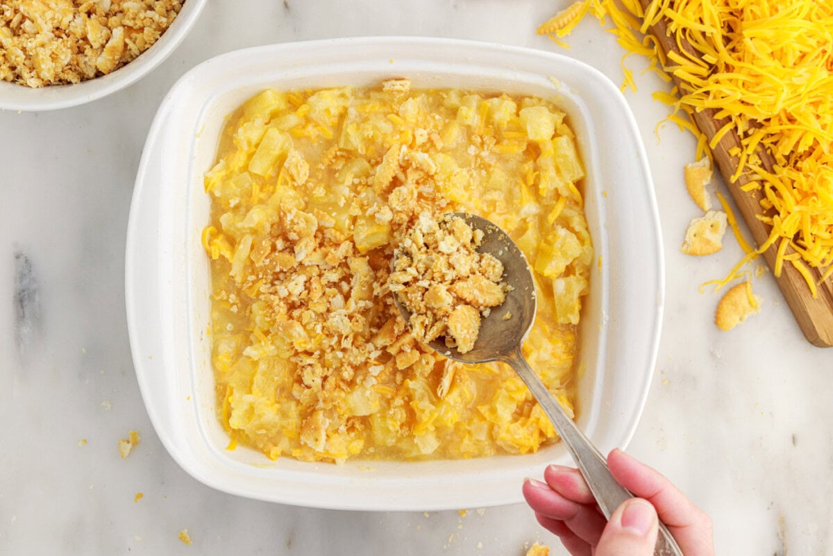 spreading ritz cracker topping over pineapple casserole