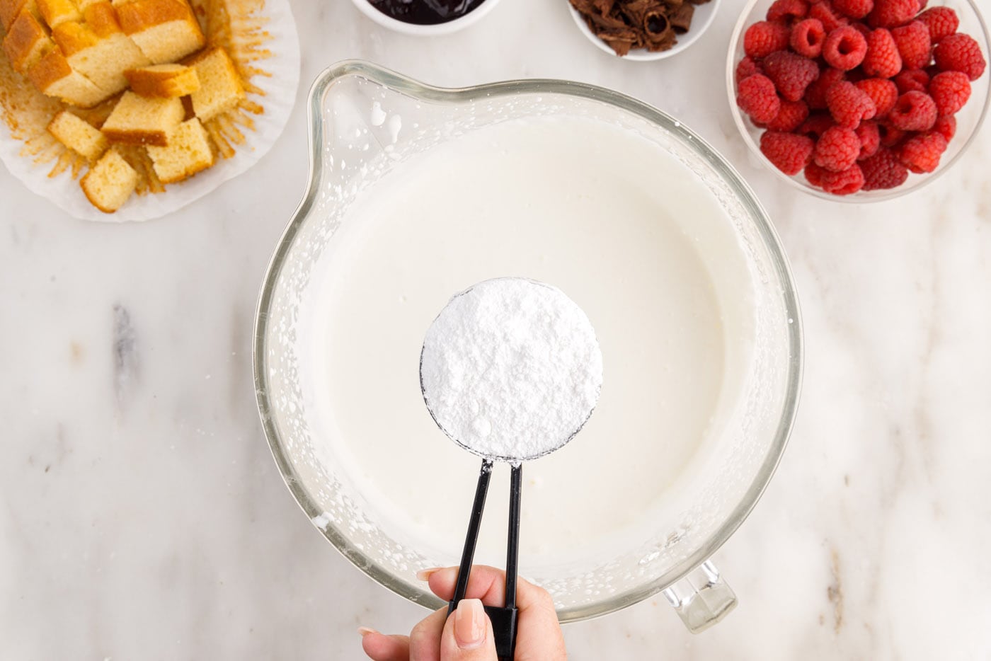 adding powdered sugar to heavy whipping cream in a bowl