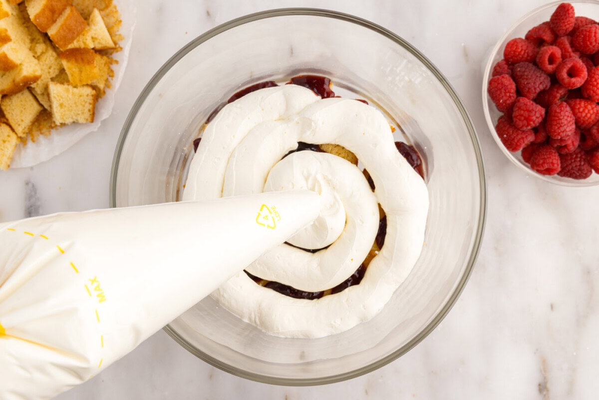 piping whipped cream cream cheese mixture over pound cake and jam