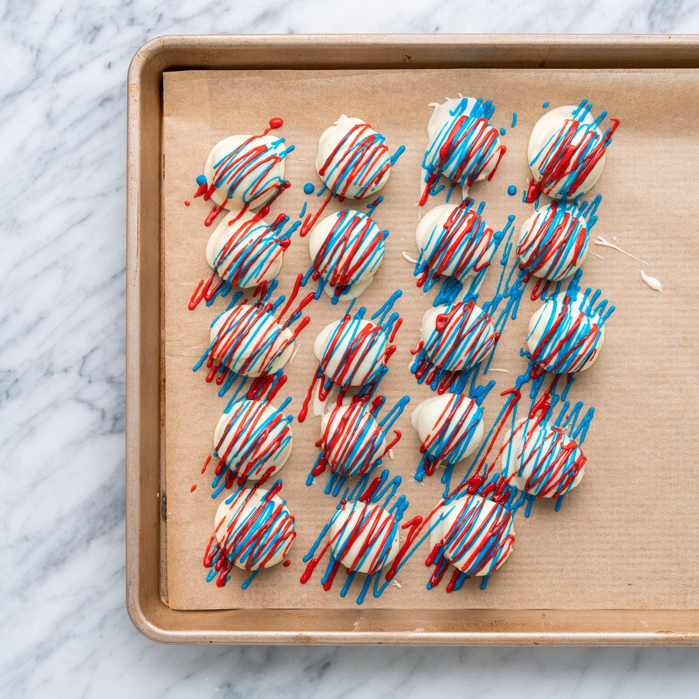 red and blue drizzled oreo truffles on a baking sheet