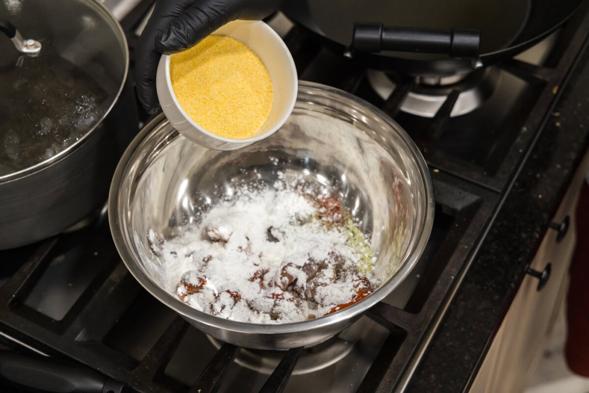 adding cornmeal to shrimp in a bowl