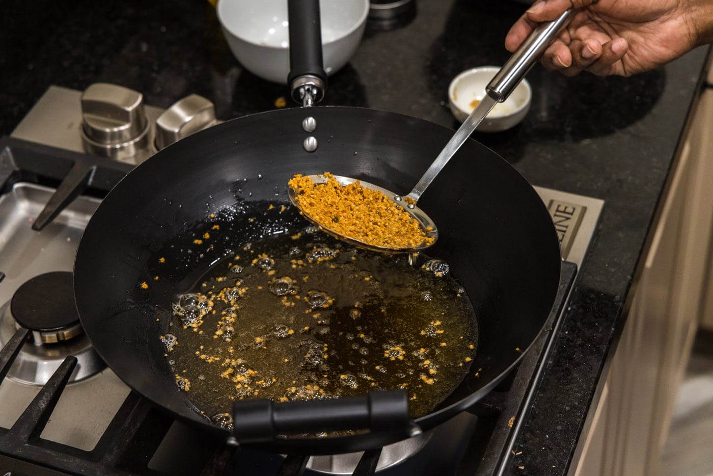 removing fried garlic from fried oil in a wok