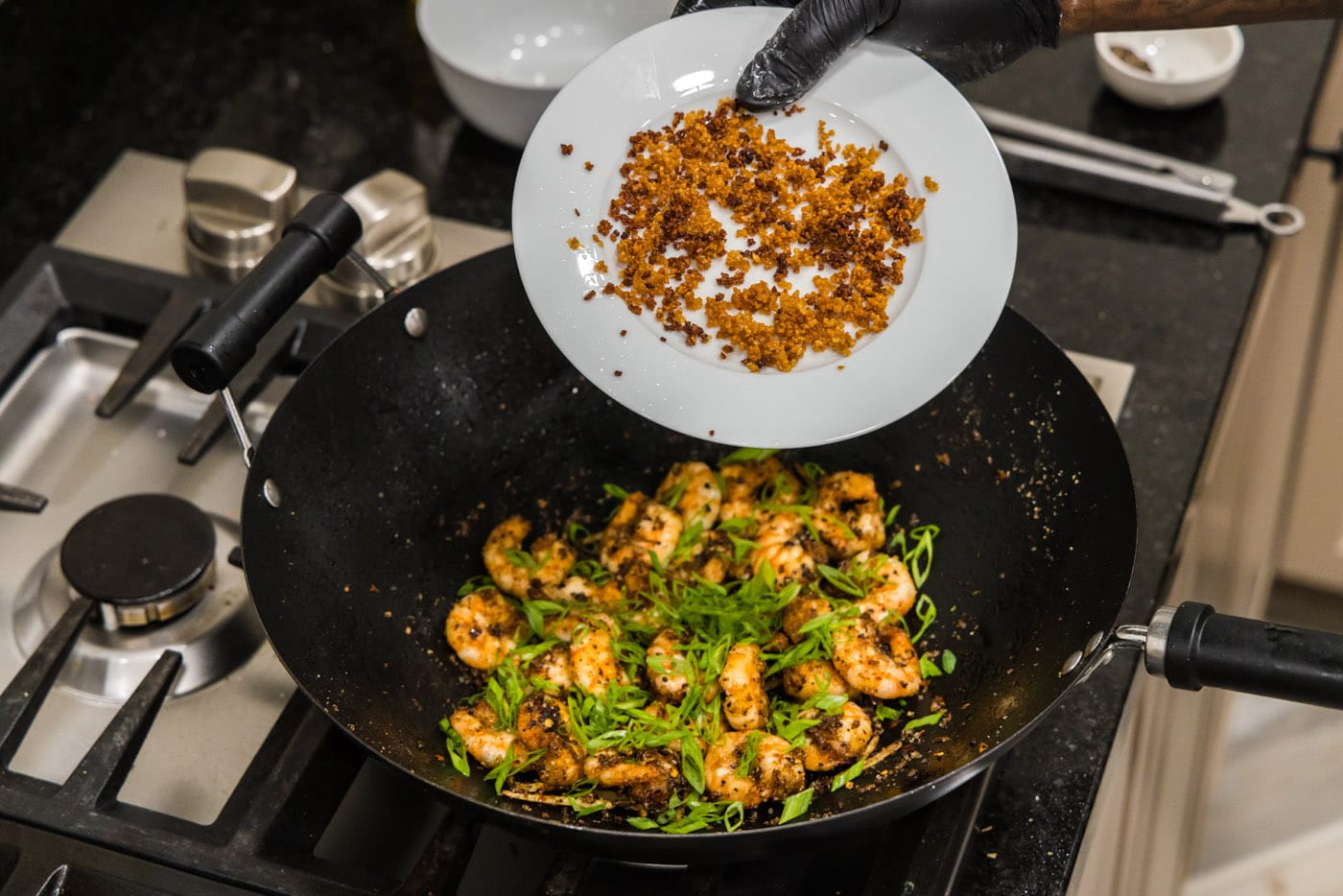 adding fried garlic to wok with salt and pepper shrimp