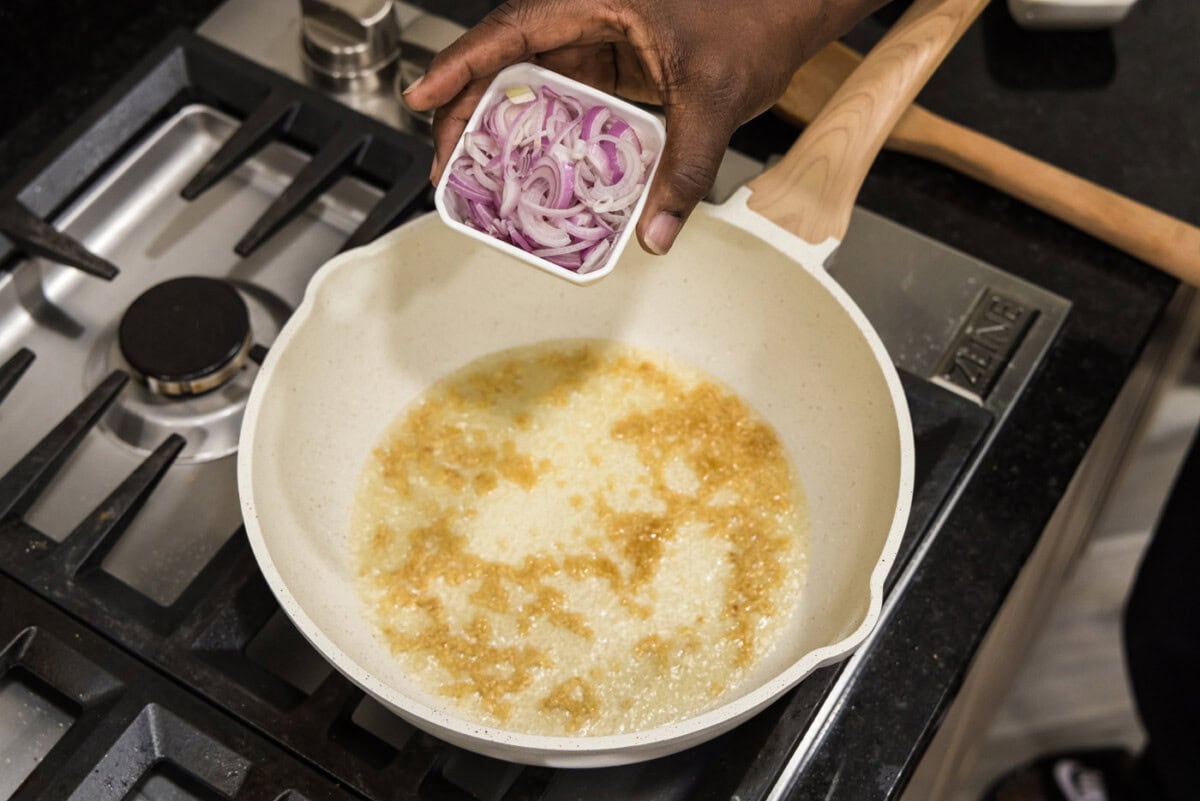 adding shallots to skillet with garlic and olive oil