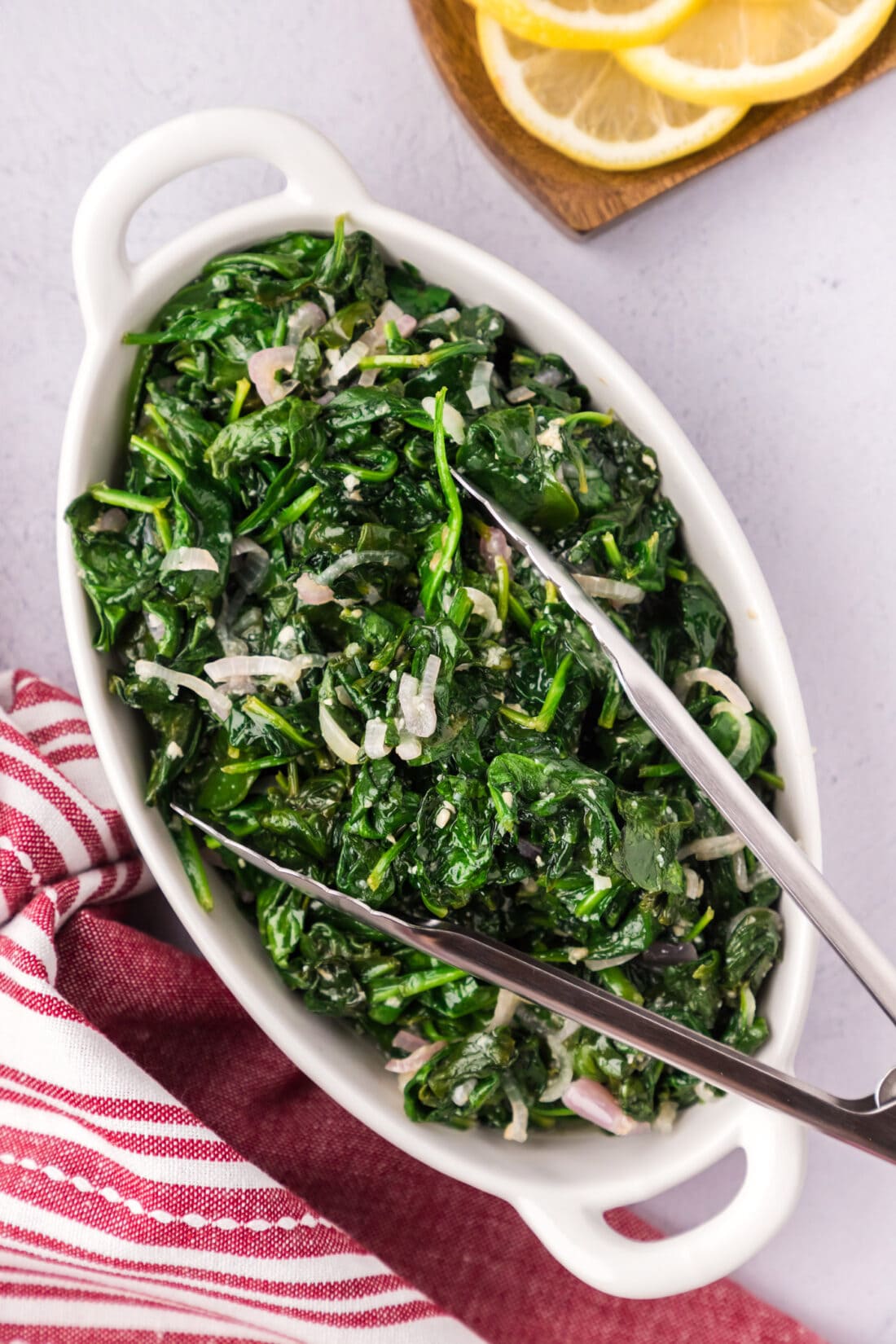 Sautéed Spinach in a serving platter with serving tongs