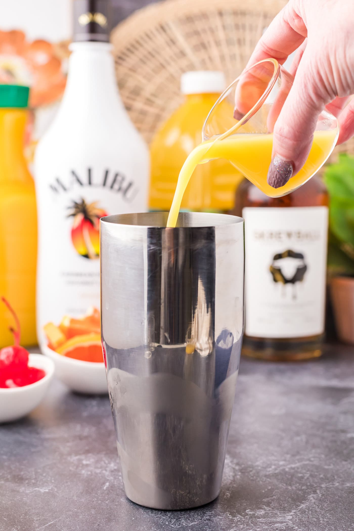 pouring juice into cocktail shaker with rum and whiskey