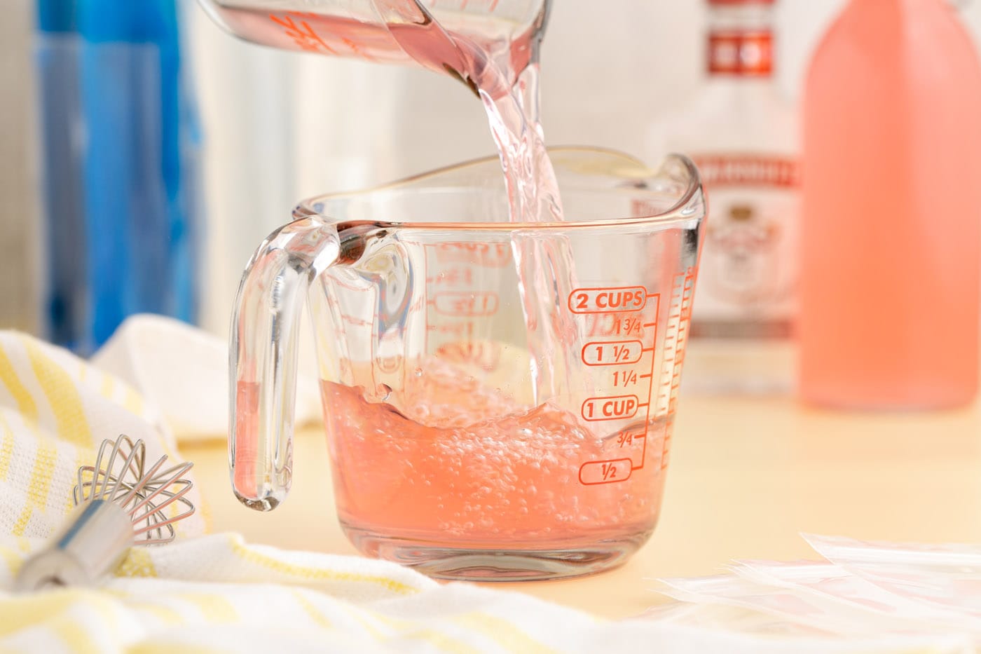 pouring juice into a measuring cup with vodka