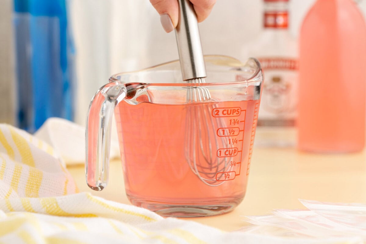whisking juice and vodka in a cup