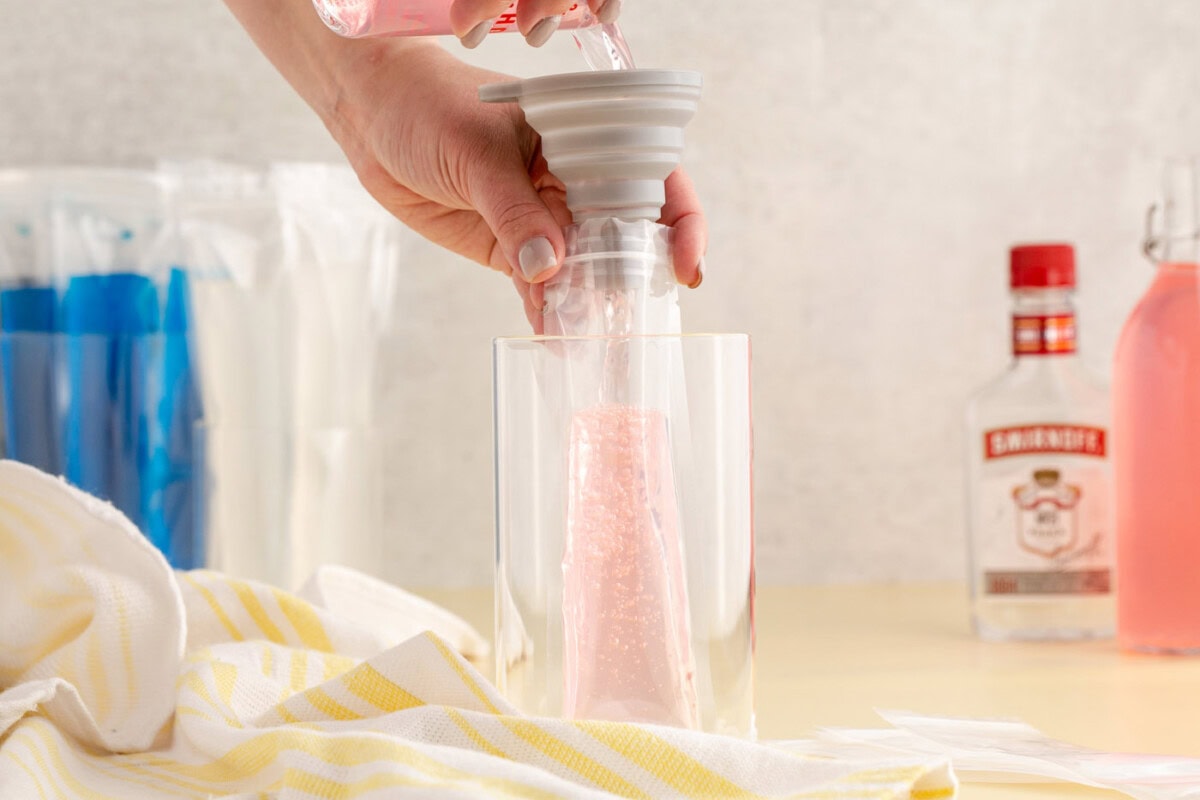 funneling vodka and juice into a popsicle sleeve