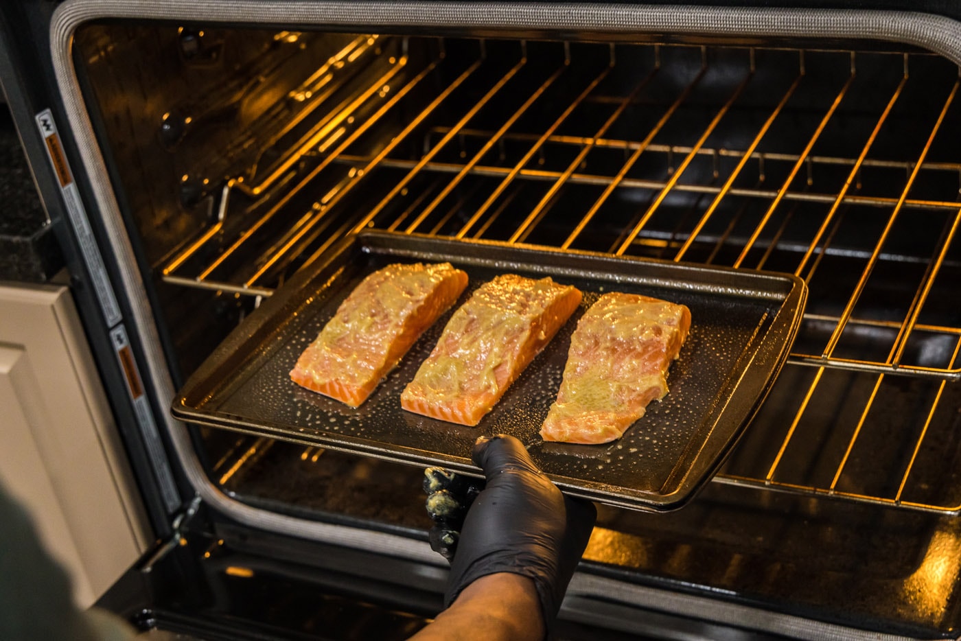hand putting salmon filets into oven