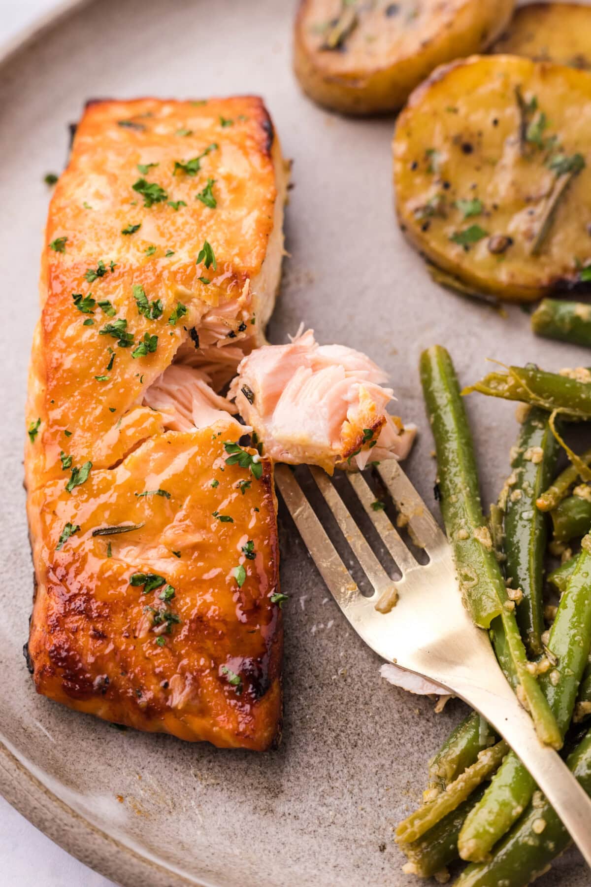 Piece of Brown Sugar Salmon on a fork next to the salmon filet 