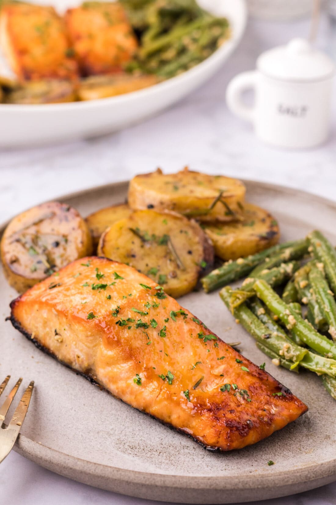 Brown Sugar Salmon on a plate with melting potatoes and garlic green beans