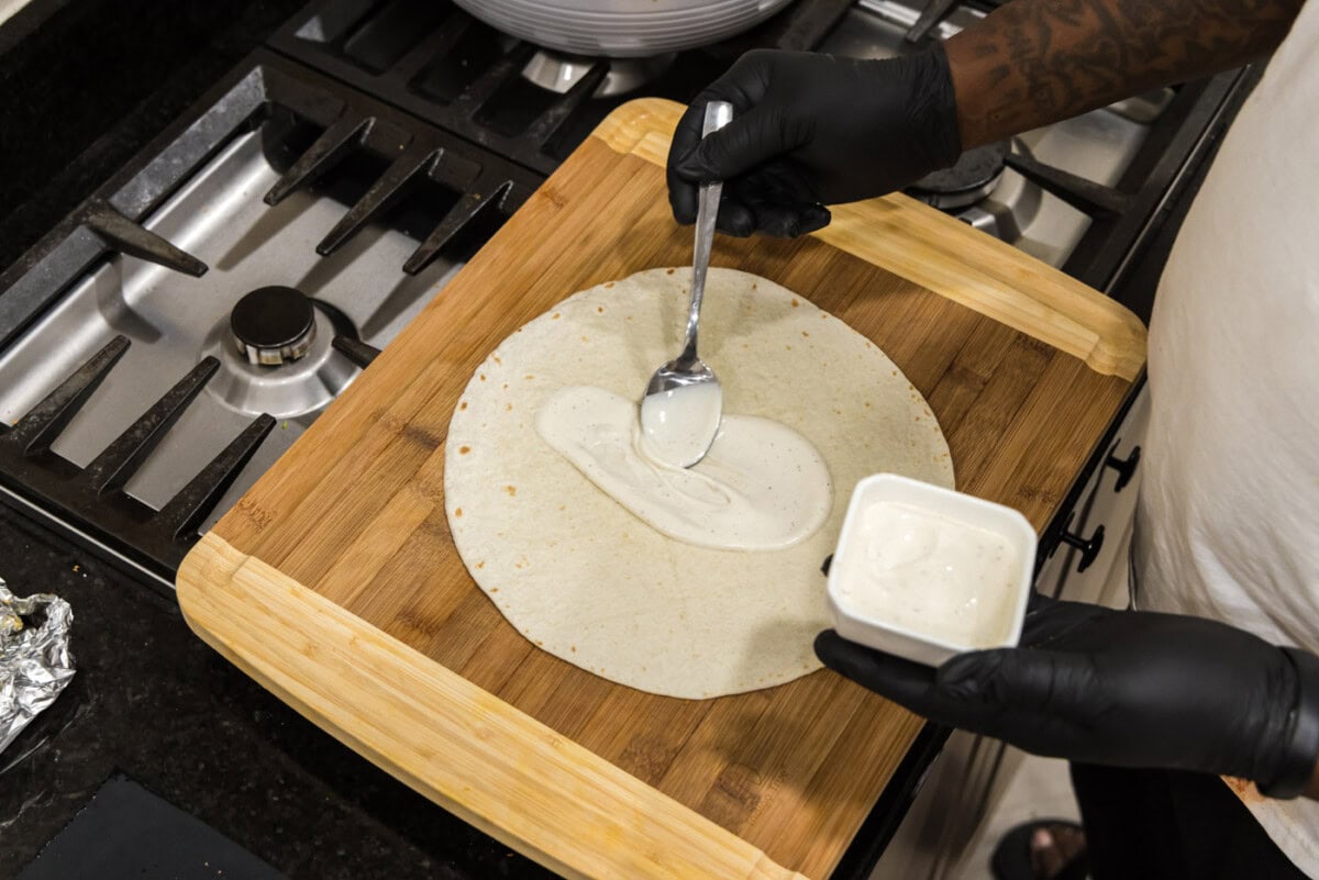spreading ranch dressing onto tortilla